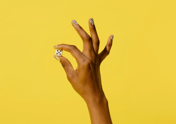 Hand Holding Dice Against Yellow Background